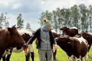 Landwirtin Theresa auf einer Wiese mit einigen ihrer Rinder. Sie steht in der Mitte der Tiere und wird von einem Rind in den Arm gezwickt.