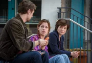Johanna "Joe" Haizinger (Katharina Stemberger, r.) sitzt zusammen mit ihrem Kollegen Ben Halberg (Daniel Gawlowski, l.) und Inga Feta (Marie Hacke, M.) auf einer Treppe in einem Innenhof.