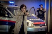 Johanna "Joe" Haizinger (Katharina Stemberger, l.) steht mit einer gezogenen Waffe im Anschlag vor einem Polizeiauto in einer Tiefgarage.