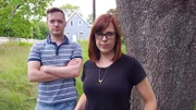 Amy Bruni and Adam Berry pose with house in background.