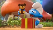 Gargamel schenkt Baby einen Teddy, mit dem er die Schlümpfe beobachten kann.