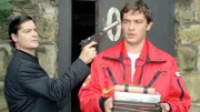 Enrico Contini (Tom Mikulla, r.) erklärt sich bereit, die Übergabe Plutonium gegen Diamanten durchzuführen. Er wird von Wörz (Fritz Karl), dem Erpresser, mit der Waffe bedroht.