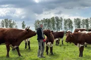 Landwirtin Theresa auf einer Wiese mit einigen ihrer Rinder.