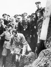 Adolf Hitler schaufelt in Frankfurt Erde, um den Grundstein für die erste deutschen Autobahn zu legen.