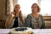 Manju (Alexandra Schalaudek, l.) und Dagmar (Johanna Gastdorf, r.) sitzen entspannt am Tisch – zwischen Kuchen, E-Zigarette und großen Plänen.