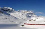 Der Bernina Express auf dem Berninapass am Lago Bianco: Der Zug schlängelt sich durch tiefe Täler, wilde Schluchten und über das ewige Eis der Bündner Alpen.