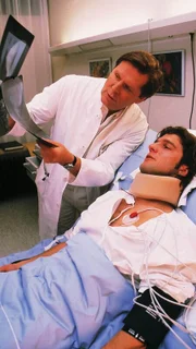 Dr. Stefan Frank (Sigmar Solbach, oben) erklärt dem Patienten Ralph Portmann (Jens Peter Nünemann) den Wirbelbruch am Röntgenbild.