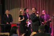 Nachdem Cheryl (Courtney Thorne-Smith, 2.v.l.) vor ihrer Cousine damit angegeben hat, in der Band von Andy (Larry Joe Campbell, l.), John (John Rubano, M.), Jim (Jim Belushi, 2.v.r.) und Beltzman (Mark Beltzman, r.) zu singen, bekommt die Band prompt eine Einladung von Mindy, um bei ihr auf der Verlobungsfeier aufzutreten. Das einzige Problem: Cheryls Stimmt ist eindeutig keine Singstimme ...