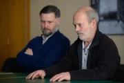 John William Cooper (Keith Allen, r.) vor dem Bewährungsausschuss. Neben ihm sitzt Craig (Simon Nehan).