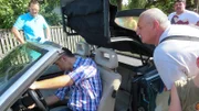 Trödelexperte Mauro Corradino (sitzend) mit einigen Kauf-Interessenten für das Auto.