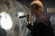 RE-ENACTMENT - Bouillard (played by Stuart Clow) walks past pieces of fuselage, stopping to look at some, he holds his flashlight at one certain point.