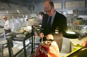 RE-ENACTMENT - Bouillard (played by Stuart Clow) inspects the red painted pices of the crash. Investigators (played by background preformers) take notes in the background. (photo credit:  Cineflix/Ian Watson)