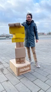 Jo Hiller an den Landungsbrücken (Hamburg) neben einem Paketstapel.