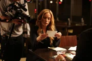 A camera points over Melissa Lewkowicz’s shoulder as she looks at a photograph.