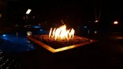 Night view of newly installed fire pits outside around the pool, as seen on Pool Kings.(BTS)