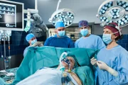 Die drei Ärzte müssen Dr. Hammersteins Schädel-Hirn-Trauma operativ versorgen. V.l.n.r. Komprse, Dr. Marc Lindner (Christian Beermann), Ben Ahlbeck (Philipp Danne), Dr. Paul Hammerstein (Norbert Hülm, liegend),  Dr. Franziska Ruhland (Gunda Ebert).