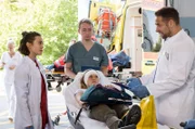 Nach einem Wanderunfall kommt Nadine Bütow (Tina Schorcht, M. mit Komparse) mit einem offenen Bruch ins Klinikum. Moreau (Mike Adler, r.) und Rebecca (Milena Straube, l.) übernehmen die Patientin.
