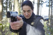 Officer Hazel zielt mit ihrer Waffe in den Wald.