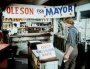 Almanzo (Dean Butler, r.) kommt zu Mrs. Oleson (Katherine MacGregor, l.) in den Laden und erfährt, dass er ebenfalls für das Bürgermeisteramt kandidiert.