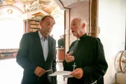 Oberst Otto Dirnberger (Dietrich Siegl, l.) zeigt Abt Bernhard Höllerer (Dietrich Hollinderbäumer, r.) den Gerichtsbeschluss, der besagt, dass alle Ordensinsassen eine Speichelprobe abgeben müssen.