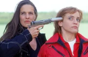 Andrea Matucini (Helen Zellweger, li.) hat gerade das gestohlene Geld umgeladen und wollte sich auf die Flucht machen als Dr. Thaler (Roswitha Meyer) sie überrascht und versucht daran zu hindern. Doch schnell hat Andrea sie in ihrer Gewalt und bedroht sie mit einer Pistole.