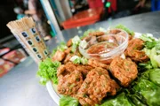 „Tod Mun Pla“, einer der beliebtesten Streetfood-Snacks in Bangkok, sind frittierte thailändische Fischlaibchen, die mit Gurke serviert und mit süßer und herzhafter Soße übergossen werden.