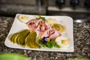 Ostervorspeise mit Osterschinken, gefüllten Eiern, verziert mit den ersten Frühlingsblumen.