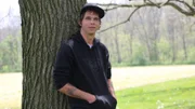 Jeremiah sitting next to a tree.