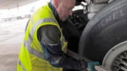 An einer Boeing 747 muss sofort einer der riesigen Reifen gewechselt werden. Der Jumbo ist soeben gelandet und soll gleich wieder starten.