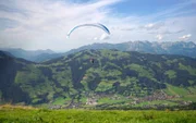 Paragleiter über dem Brixental mit Blick auf den Wilden Kaiser.
