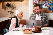 Gregor (Holger Matthias Wilhelm) bestellt online neue Bettwäsche; Theresa (Ursula Erber) schaut ihm dabei über die Schulter.