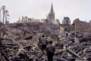 Eine US-Infanteriepatrouille bahnt sich einen Weg durch die Ruinen von Saint Lô. Die französische Stadt wird im Zweiten Weltkrieg zu 95 Prozent zerstört.