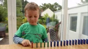 In der „Sendung mit dem Elefanten“ geht es um Bewegung. In einer Zeitlupenaufnahme gibt es zu sehen, wie die Dominosteine nach und nach umfallen.
