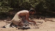 Fernando kneeling down and starting a fire.