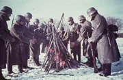 Deutsche Soldaten an der Ostfront wärmen sich an einem Feuer.