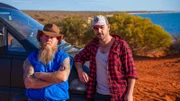 Rod Manning [left] and James "JC" Caruana [right] standing on red dirt in Shark Bay, in front of the road trip car the 'Deli'.