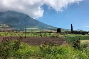 Landschaft jenseits des Karibik-Klischees. Aus dem Zug blickt man auf den erloschenen Vulkan und die Relikte der Zuckergewinnung, Mühlen und Schornsteine.