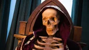 A close up of the skeleton earing a purple cloak