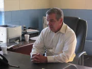 The investigator on Michelle's case sitting at his desk.