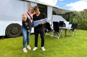 Sofia (M) und Carsten Rudolf mit ihrem Sohn Paul vor ihrem zum Wohnmobil ausgebauten Linienbus.