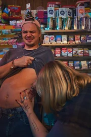 Augen zu und durch: Fred (Wilson Gonzalez, l.) muss die Zähne zusammenbeißen während Fibi (Kiara Hollatko, r.) ihm ein Tattoo sticht.