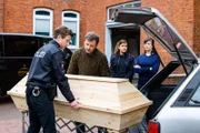 Henk Cassens (Maxim Mehmet,li.) hat ein Problem: Er muss seine tote Tante aus dem Beerdigungsinstitut Mohn holen, sonst besteht die Gefahr der Vorteilnahme im Amt. Zusammen mit Patrick Diekmann (Nicholas Reinke, 2.v.l.) hievt er den Sarg in dessen Wagen. Süher Özlügül (Sophie Dal, M.) und Marion Mohn (Julia-Maria Köhler, r.) stehen beobachtend daneben.