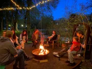 Bewohner des Münzinghofs sitzen abends am Lagerfeuer zusammen.