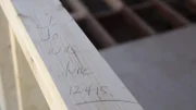 Joanna Gaines leaves her mark on a beam in the Ward's carriage house while Chip works to frame out new walls, as seen on Fixer Upper.