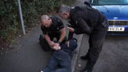 Polizeibeamte legen dem Verdächtigen Handschellen an.