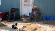 Ken and Christine sitting outside their homestead with their dogs