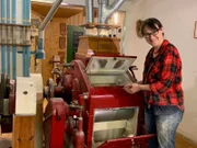 Am Walzenstuhl kann Petra Schuster  einstellen, wie fein die Walzen das Getreide zerkleinern sollen.