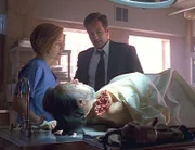Scully (Gillian Anderson, l.) und Mulder (David Duchovny, r.) betrachten die Leiche des großen Zauberers Maleeni (Ricky Ray, liegend).