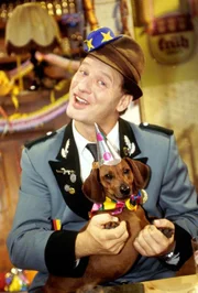 Dieter Krause begeht Karneval mit seinen Freunden vom Dackelclub in gewohnt militärischer Form. Dackel Bodo ist mit einem festlichen Hütchen geschmückt und lässt das Programm stoisch über sich ergehen.