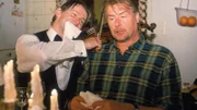 Horst (Frank Vockroth, r.) wollte Rita mit einem leckeren Abendessen und einem Stehgeiger (Max Herbrechter) überraschen, doch sie taucht einfach nicht auf. Er ahnt nicht, dass sie bei dem Versuch Bernie aus dem Crown-Markt zu befreien in einem Lüftungsschacht stecken geblieben ist.